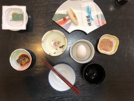 Breakfast of mackerel, natto (top left), squid, raw egg and fish paste